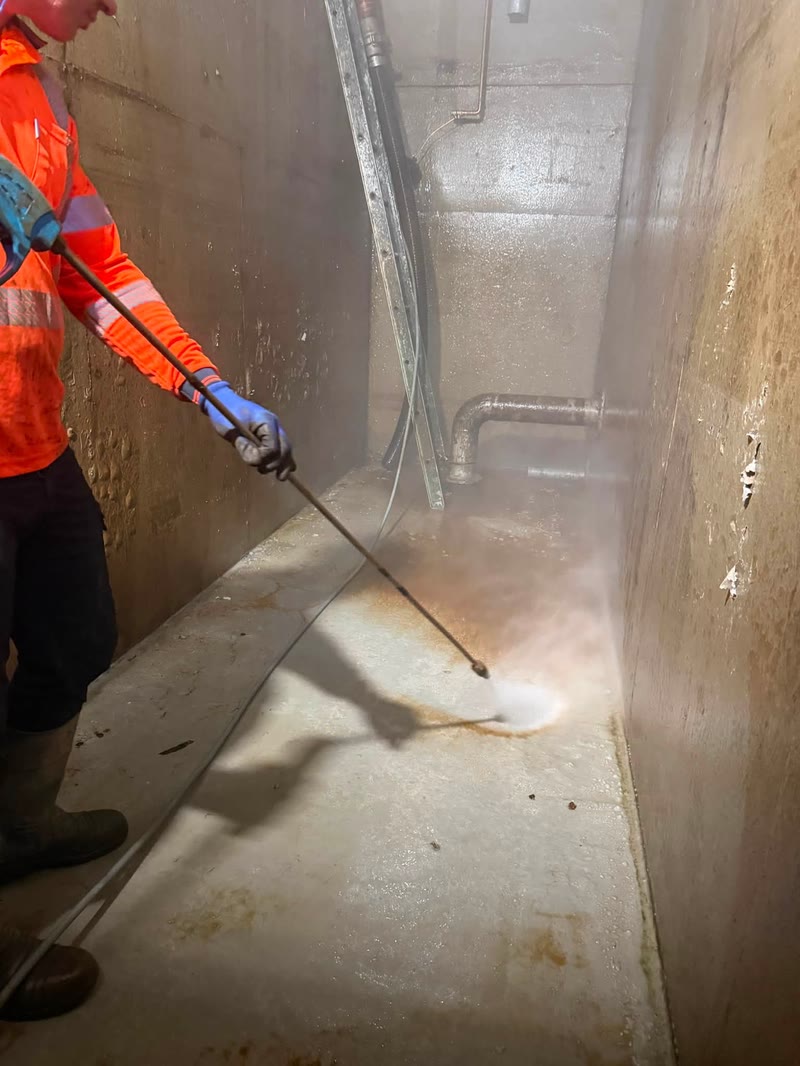 Worker cleaning a concrete area with vacuum equipment