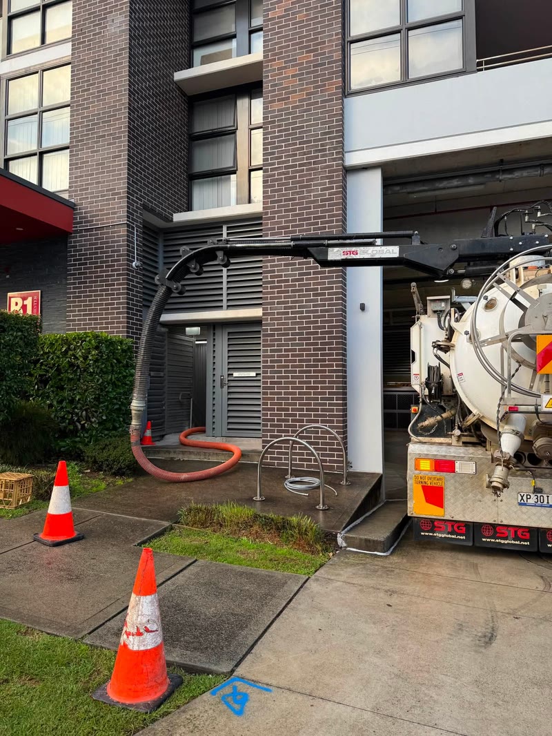 Vacuum truck operating beside a multi-storey building