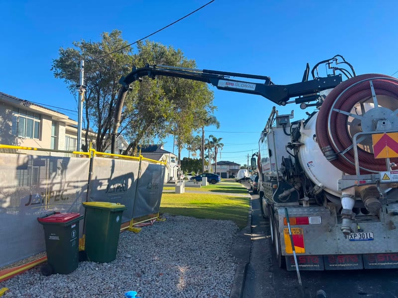 Vacuum truck and extended boom set up beside a work area