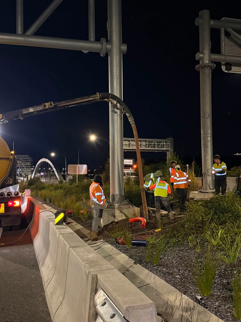 Night works with vacuum equipment beside a road barrier