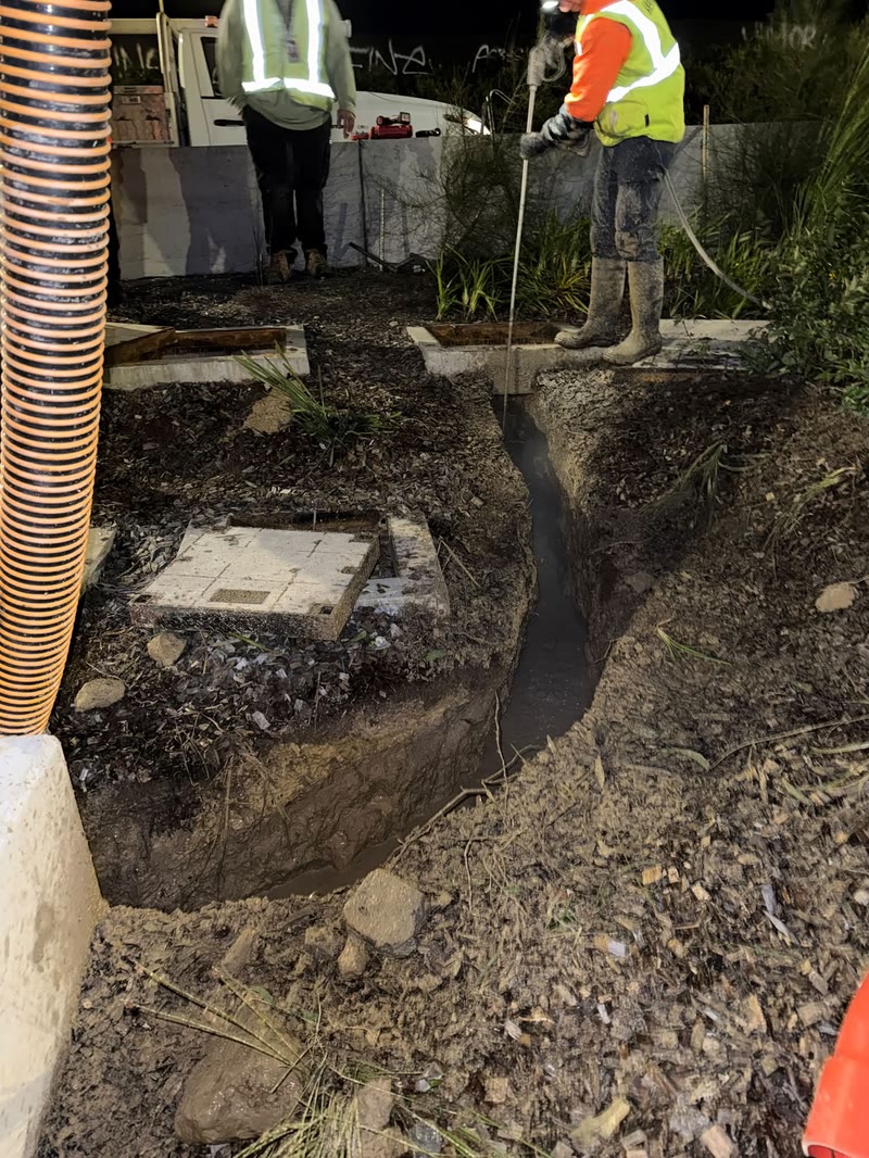 Worker excavating soil with a vacuum hose