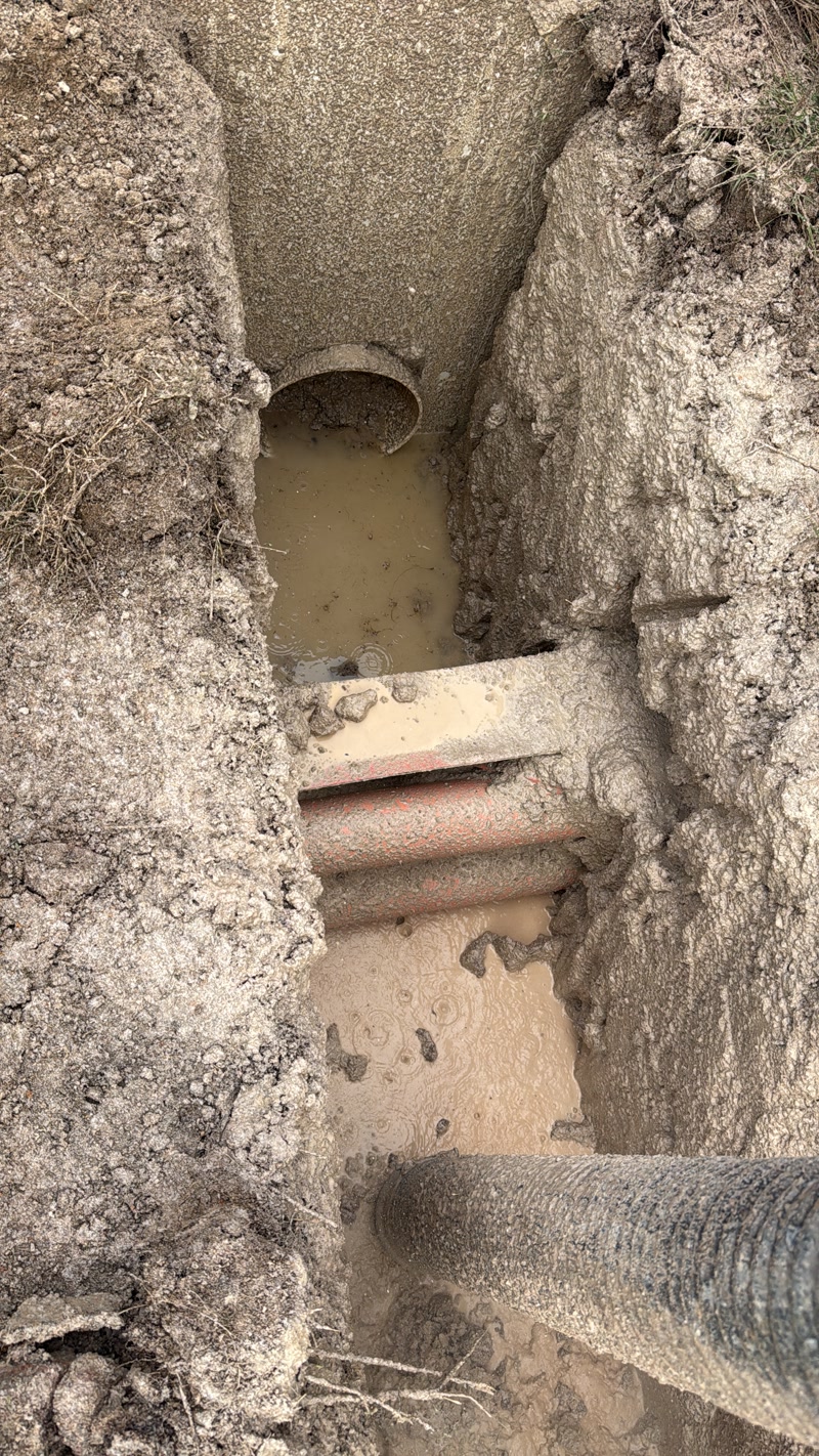 Exposed pipe within a narrow soil excavation