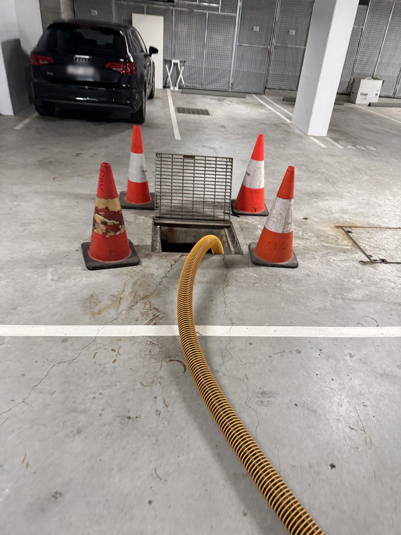 Suction hose running into a drainage pit inside an undercover car park