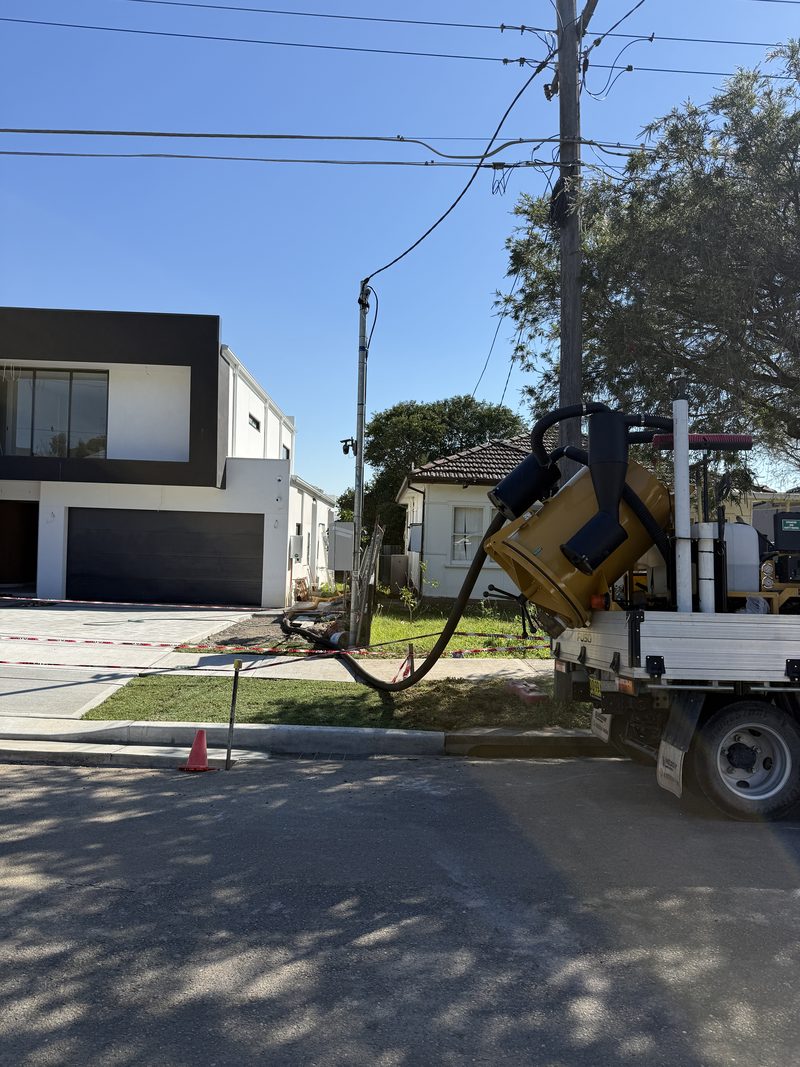 Compact vacuum unit on a truck tray working on a residential street verge