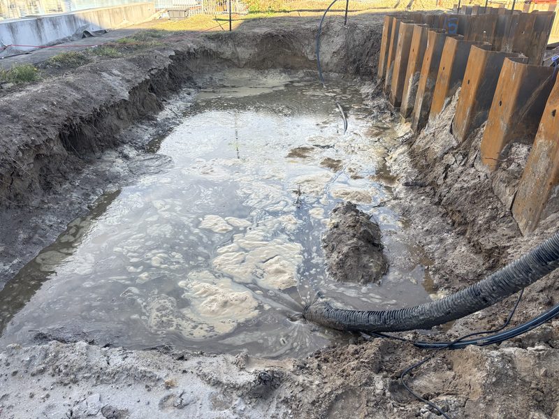 Water-filled shored excavation with a suction hose running into it