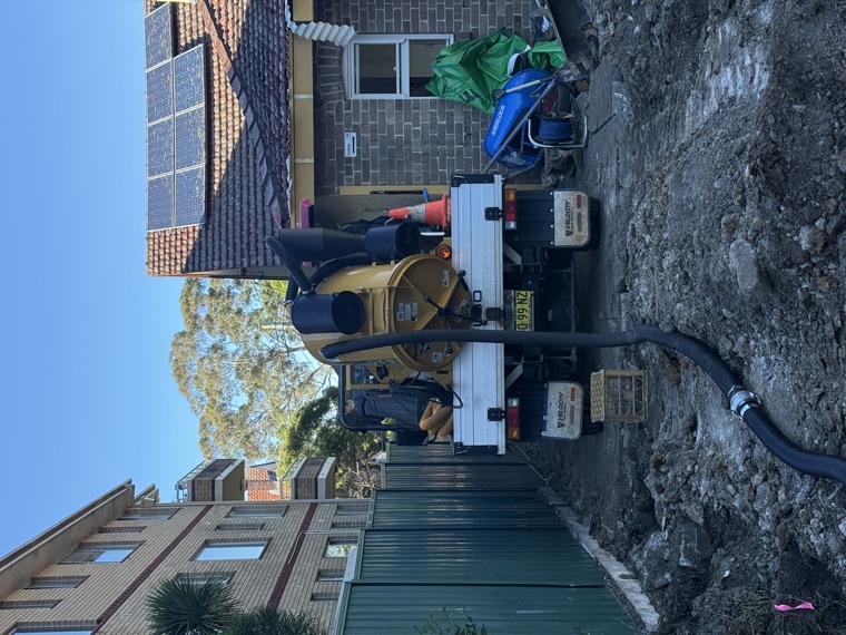 Compact yellow vac truck on residential driveway hydro excavation Sydney