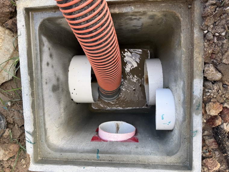 Orange suction hose removing sludge from drainage pit Sydney